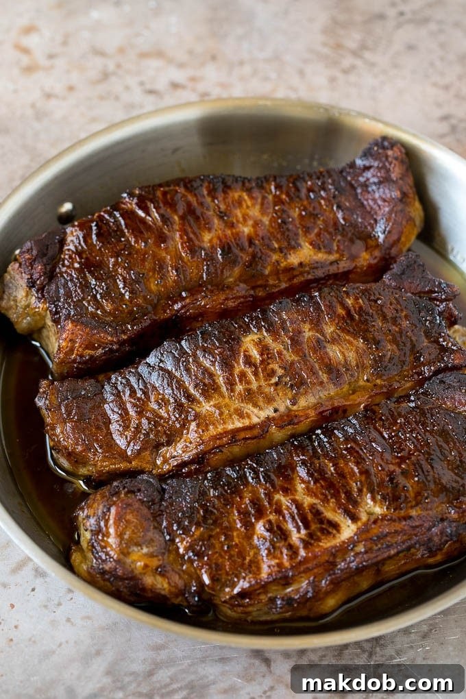 Seared strip steaks in a skillet with a beautiful brown crust.