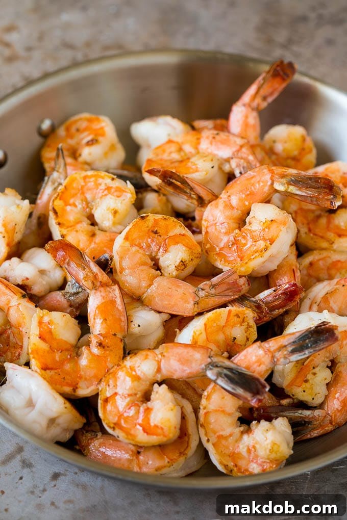 Sauteed jumbo shrimp in a skillet, perfectly pink and opaque.