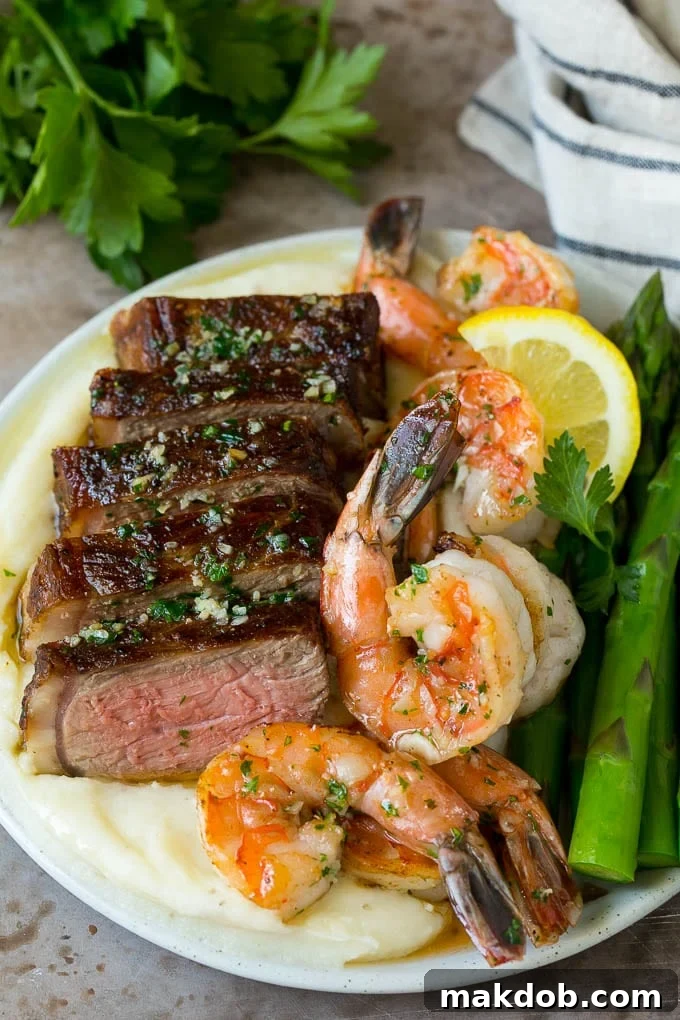 Surf and turf with steak, shrimp, mashed potatoes and asparagus, plated beautifully.