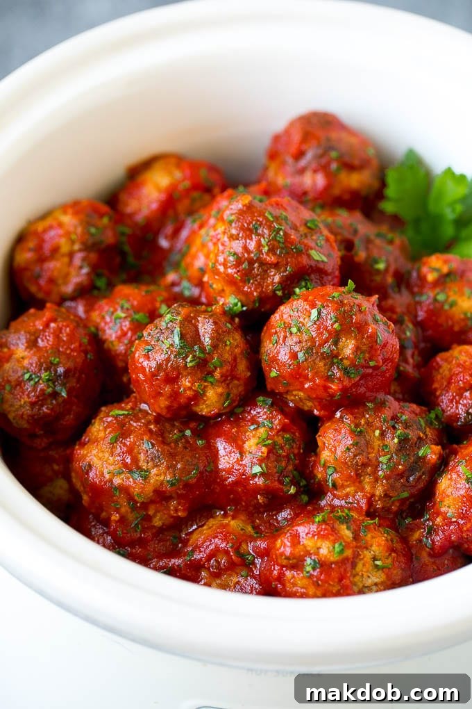Turkey meatballs simmering in a rich tomato sauce inside a slow cooker, garnished with fresh parsley.