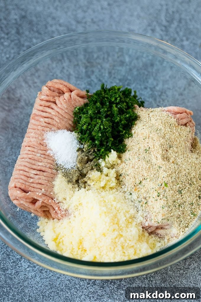 A bowl of lean ground turkey mixed with Italian breadcrumbs, fresh parsley, minced garlic, onion powder, an egg, Parmesan cheese, salt, and pepper.