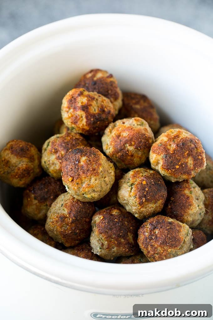 Beautifully browned turkey meatballs nestled in rich tomato sauce inside a slow cooker, ready for simmering.