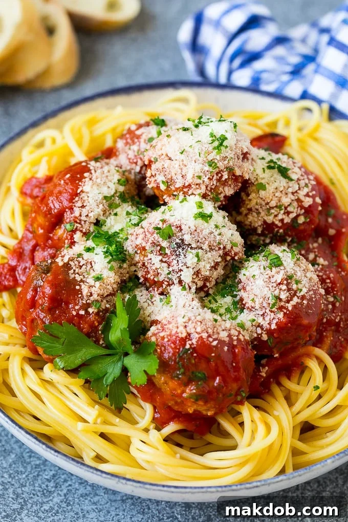 A beautifully plated bowl of spaghetti topped with tender turkey meatballs and a generous sprinkle of grated Parmesan cheese.