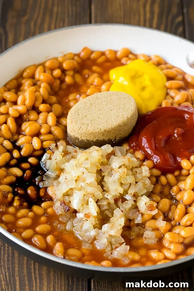 Smoky Bacon Baked Beans 3 Beans in a pan with onions, molasses, brown sugar, ketchup and mustard.