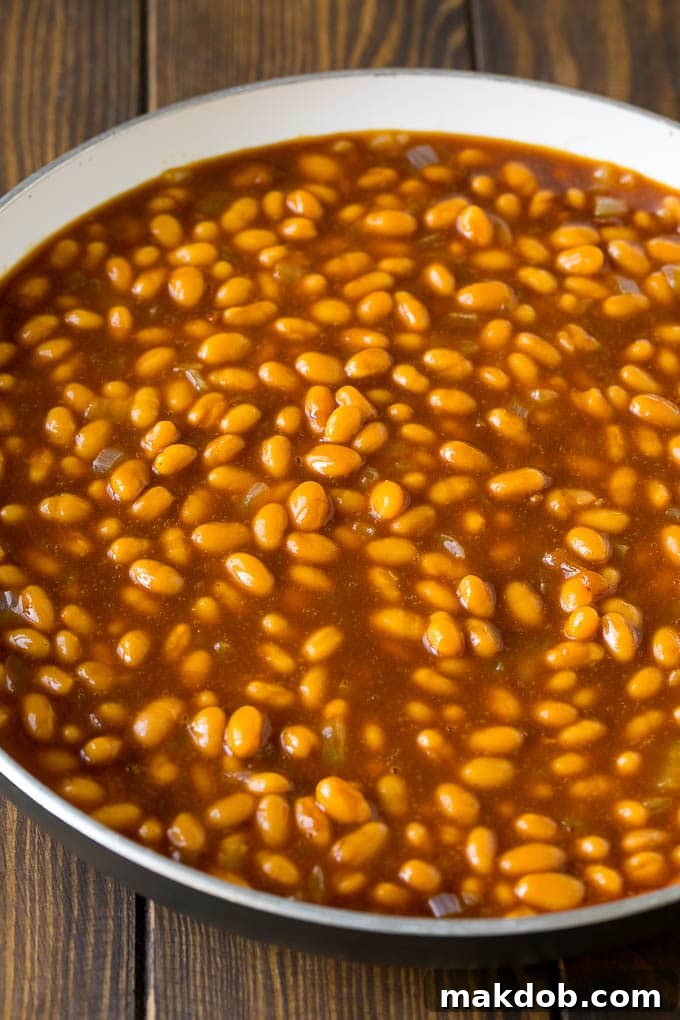 Smoky Bacon Baked Beans 4 Beans mixed with sauce ingredients in a pan.