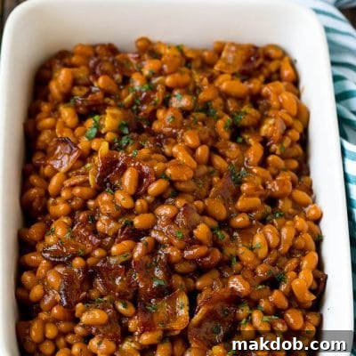 Bacon baked beans in a serving dish garnished with parsley.