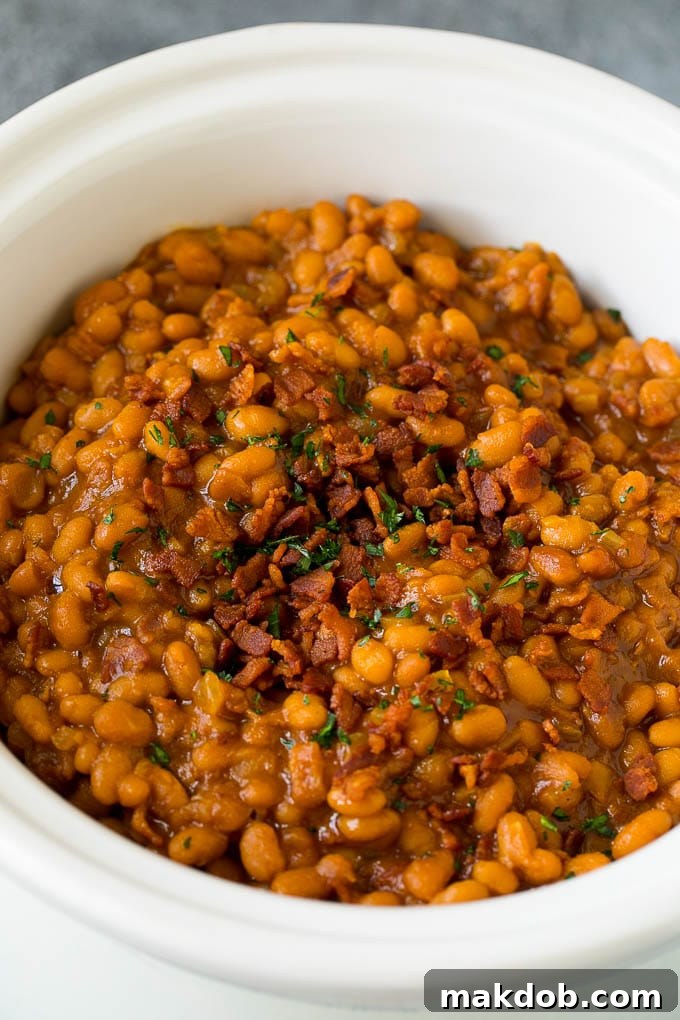 Crock Pot Baked Beans | Slow Cooker Baked Beans #beans #bacon #slowcooker #crockpot #dinneratthezoo Slow cooker baked beans topped with bacon and parsley.