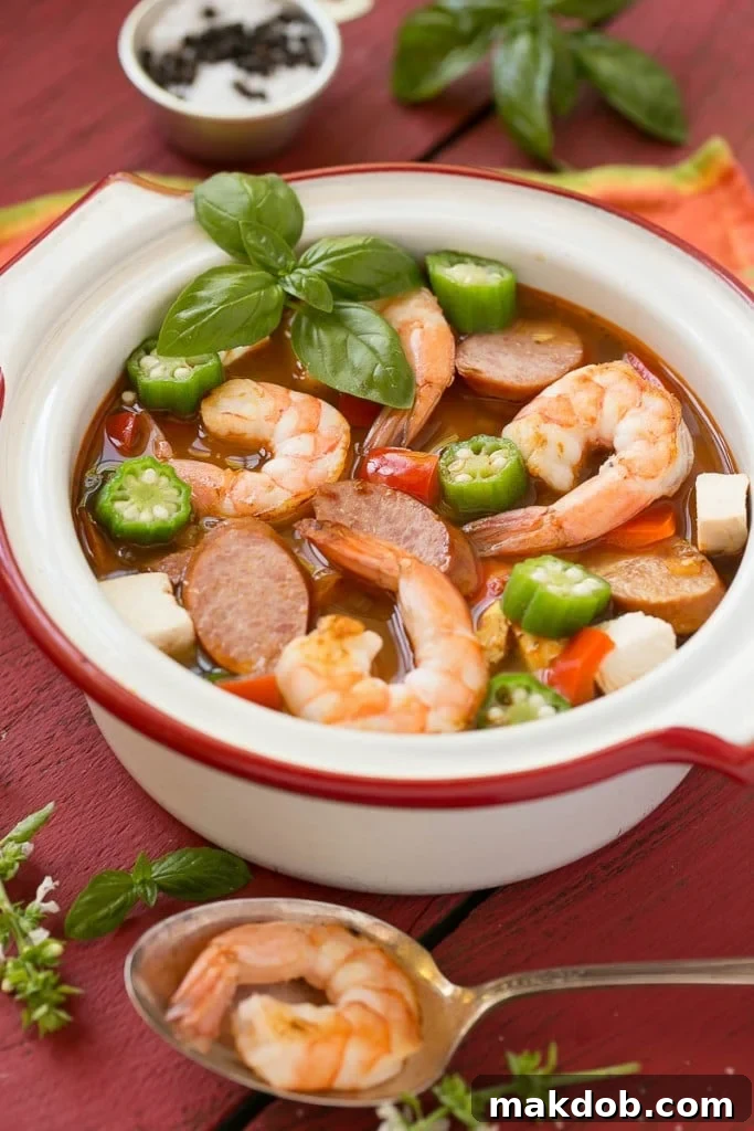 Single Skillet Surf & Turf Gumbo 4 Close-up of a steaming bowl of healthy One Pot Chicken and Shrimp Gumbo, showcasing chicken pieces, shrimp, sausage, and colorful vegetables, ready to eat in 30 minutes.