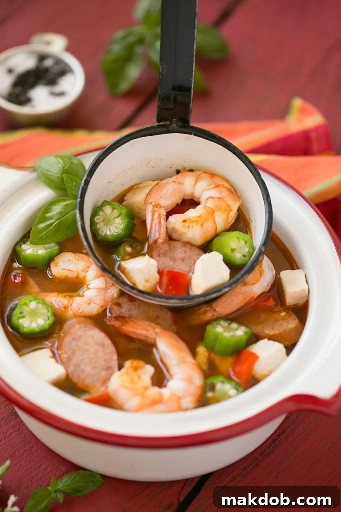 Single Skillet Surf & Turf Gumbo 8 A close-up of the One Pot Chicken and Shrimp Gumbo in a serving bowl with a spoon, ready to be enjoyed as a quick and healthy 30-minute meal.