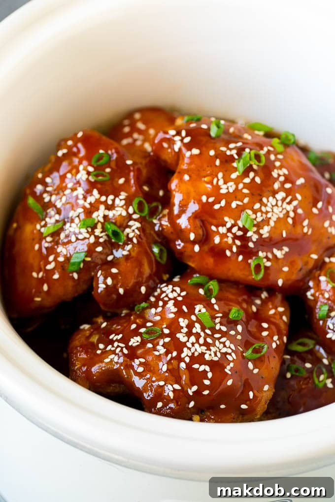Slow cooker chicken thighs garnished with vibrant sesame seeds and fresh green onions, ready to be served.