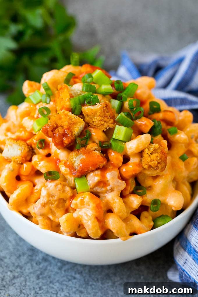 Buffalo Chicken Mac and Cheese Recipe | Spicy Macaroni and Cheese #chicken #buffalochicken #macandcheese #cheese #dinner #pasta #dinneratthezoo Kereviz ve yeşil soğanla süslenmiş bir kase buffalo tavuklu makarnayla peynir.