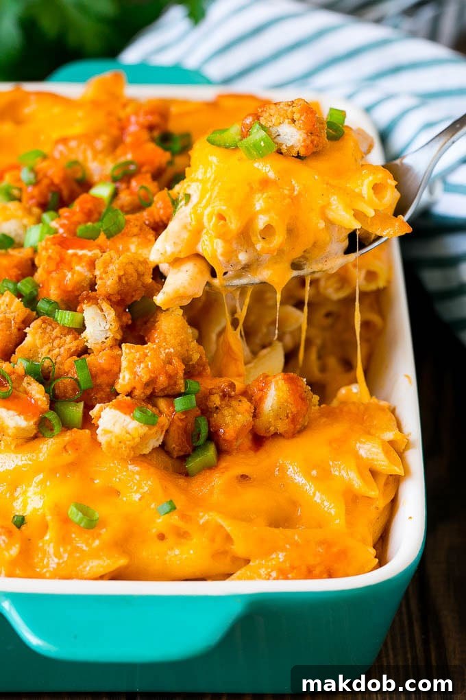 A spoon serving up a portion of buffalo chicken pasta, showcasing melted cheese and chicken pieces.