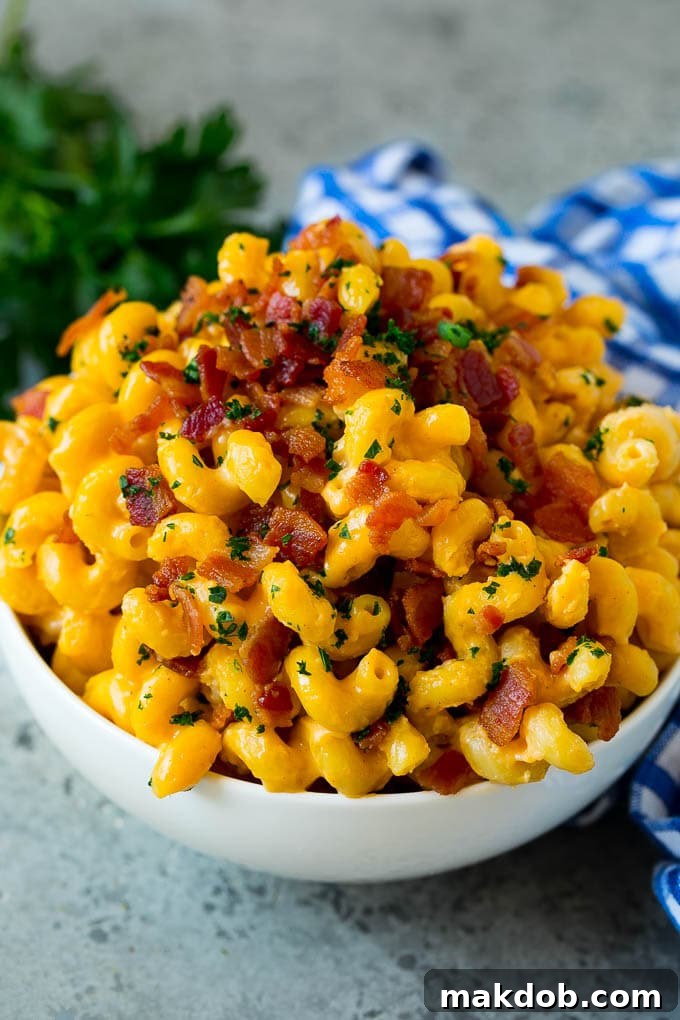 A bowl of bacon mac and cheese topped with chopped parsley.