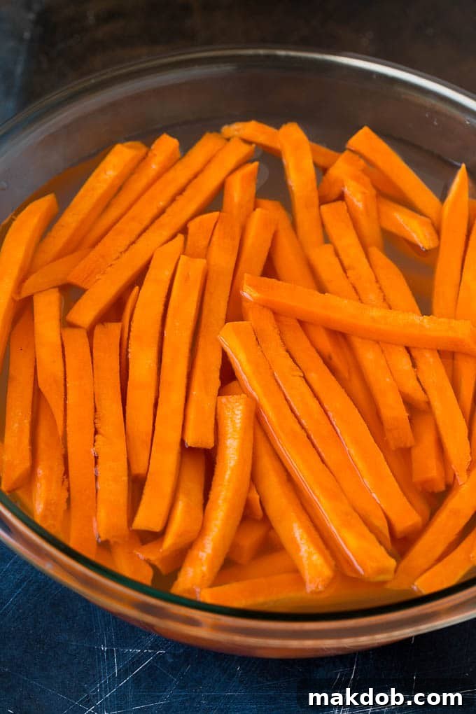 Sweet Potato Fries Recipe | Baked Sweet Potato Fries | Homemade Fries #fries #sweetpotato #sidedish #frenchfries #dinner #dinneratthezoo Strips of sweet potato in a bowl of water.