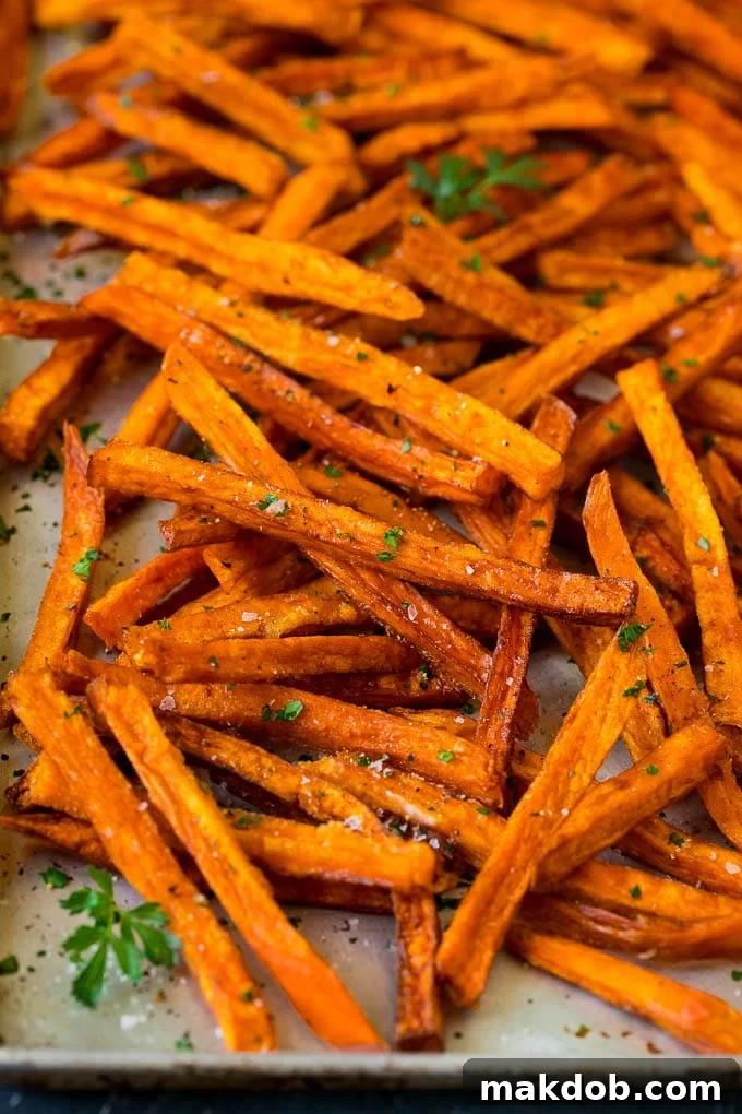 Sweet Potato Fries Recipe | Baked Sweet Potato Fries | Homemade Fries #fries #sweetpotato #sidedish #frenchfries #dinner #dinneratthezoo Sweet potato fries on a sheet pan, topped with salt, pepper and parsley.