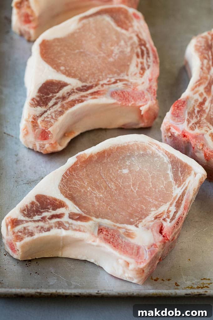 Raw pork chops on a sheet pan.