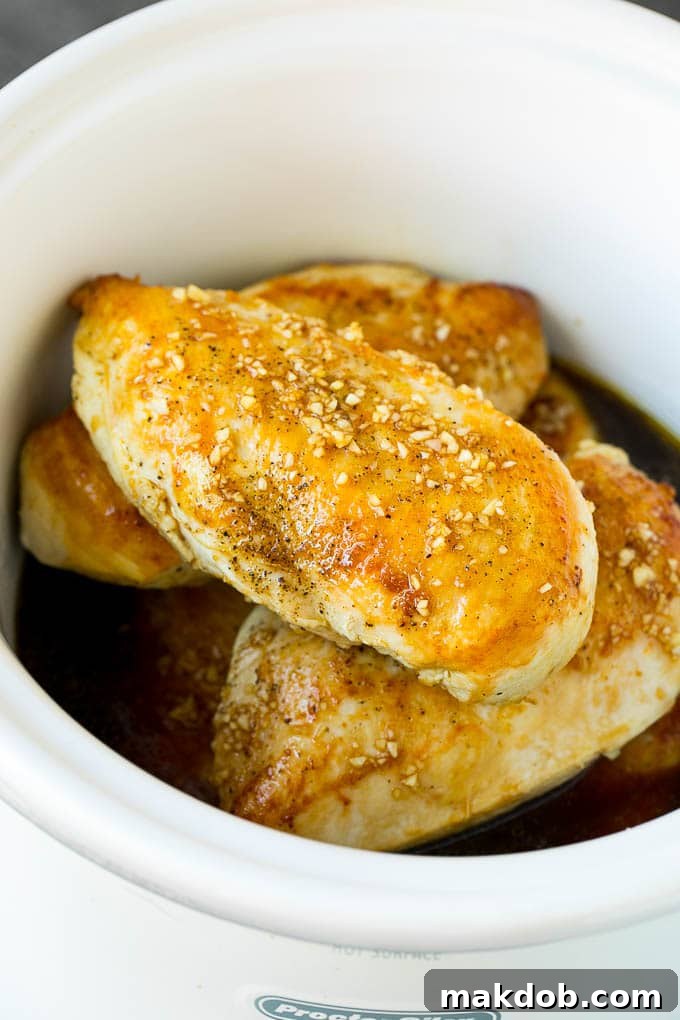 Slow Cooker Chicken Breast Recipe | Crock Pot Chicken Breast | Chicken and Gravy Chicken breasts with garlic and herb sauce poured over the top, garnished with parsley.
