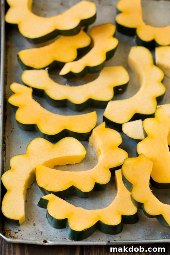 Freshly sliced acorn squash arranged on a sheet pan, ready for roasting.