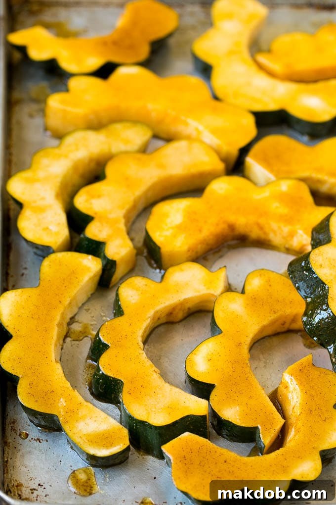 Acorn squash slices beautifully coated in a sweet and savory mixture, ready for the oven.
