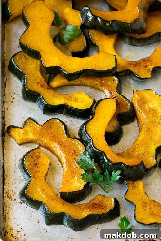 Cinnamon-roasted acorn squash slices, golden and caramelized, on a baking sheet.