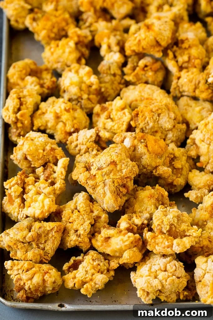 Golden-brown, breaded, and fried chicken thigh pieces piled on a plate.