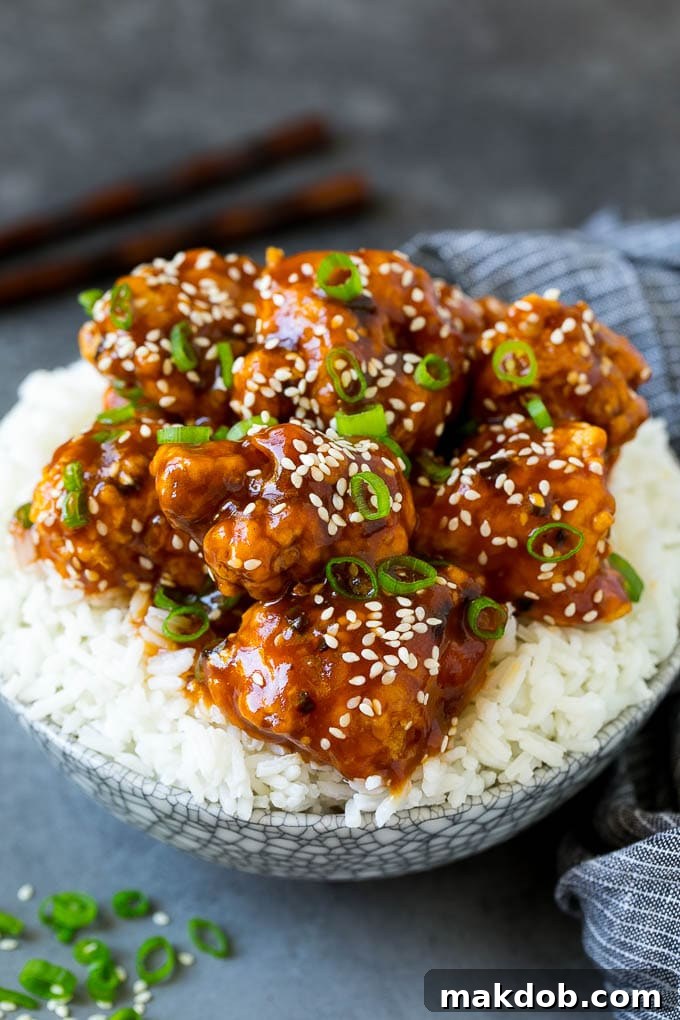 General Tso's chicken served over a bed of fluffy steamed white rice, garnished with green onions.