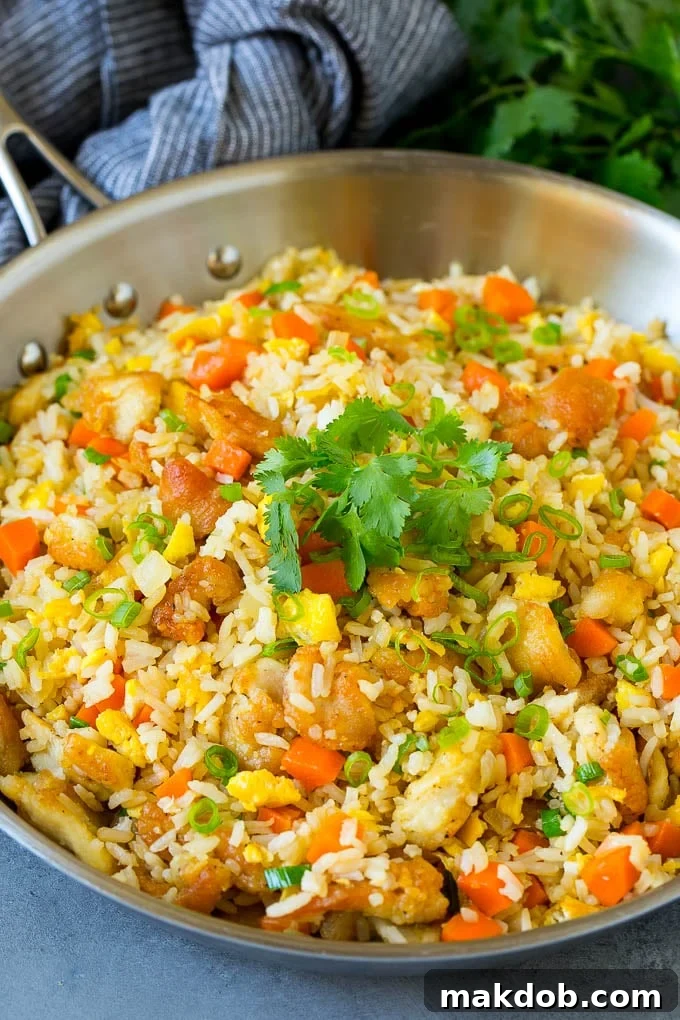 Thai fried rice in a skillet with chicken and mixed vegetables.