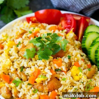 A plate of Thai fried rice garnished with cucumbers and tomatoes.