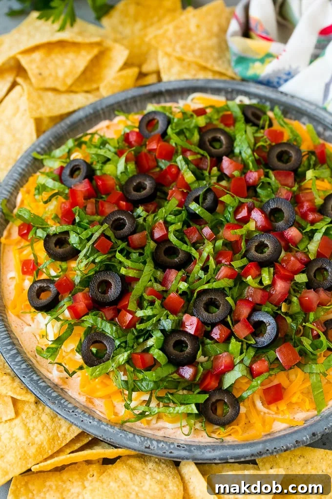 Taco dip with layers of seasoned cream cheese, lettuce, tomato, shredded cheese and olives.