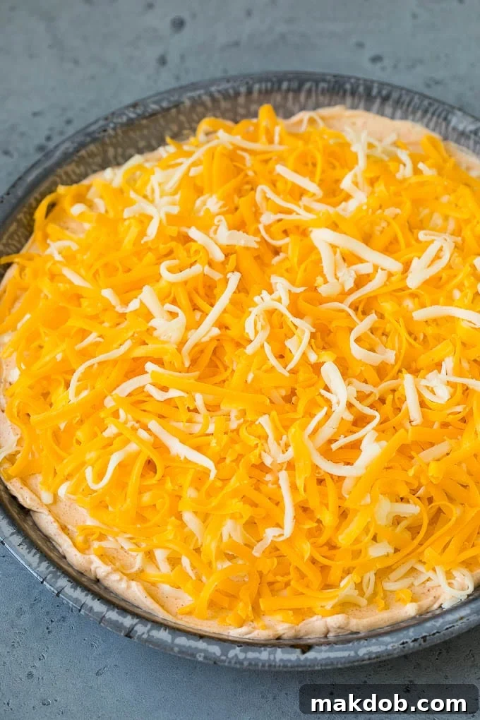 Shredded cheese sprinkled over taco flavored cream cheese and sour cream.