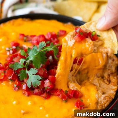 Creamy Spicy Bean Dip 2 A tortilla chip scooping out a serving of Mexican bean dip.