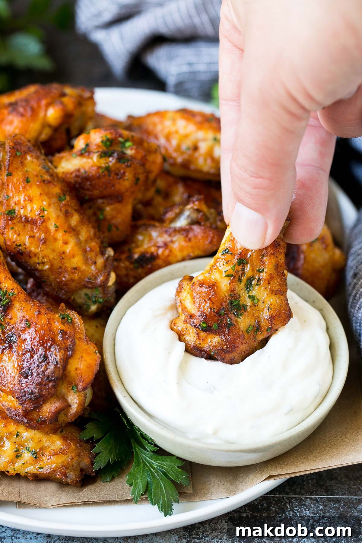 Crispy Oven Wings 6 A hand dipping a chicken wing into ranch dip.