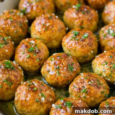 Chicken meatballs in a skillet of garlic butter.