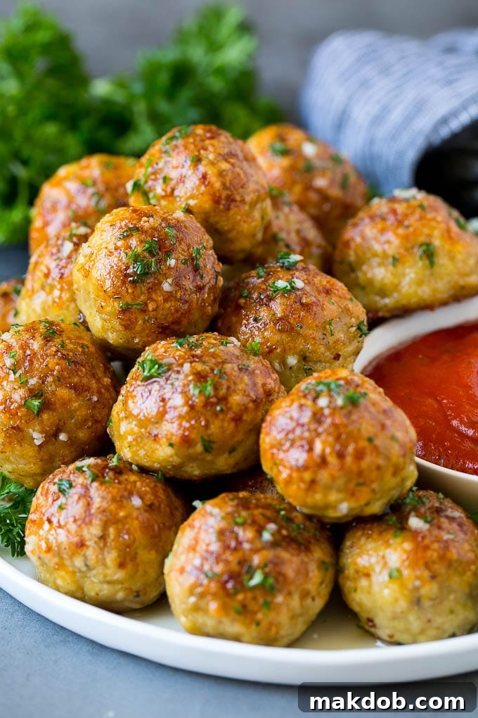 A vibrant serving plate of golden-brown chicken meatballs, generously coated in rich marinara sauce and garnished with fresh basil leaves, ready to be enjoyed.
