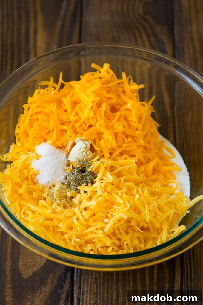 A bowl of milk, cream, two types of shredded cheese and seasonings, ready for mixing.