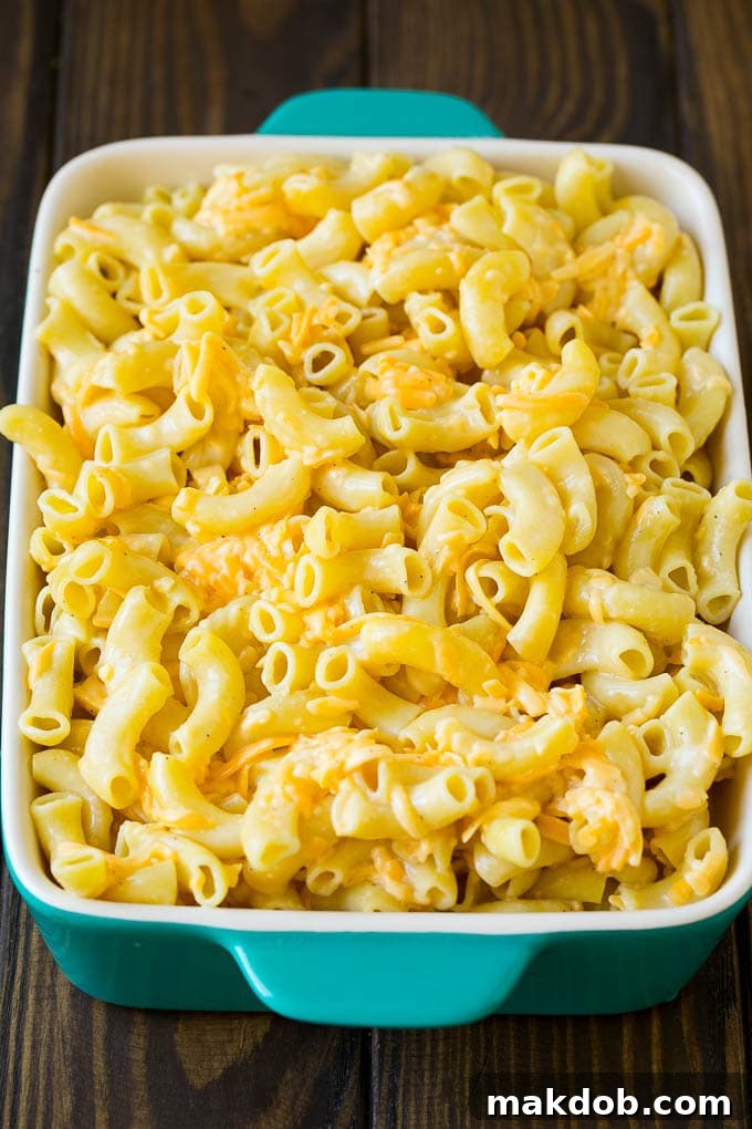 Macaroni noodles tossed with eggs, milk, and cheddar cheese in a large bowl.