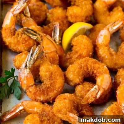Fried shrimp on a sheet pan garnished with parsley and lemon.