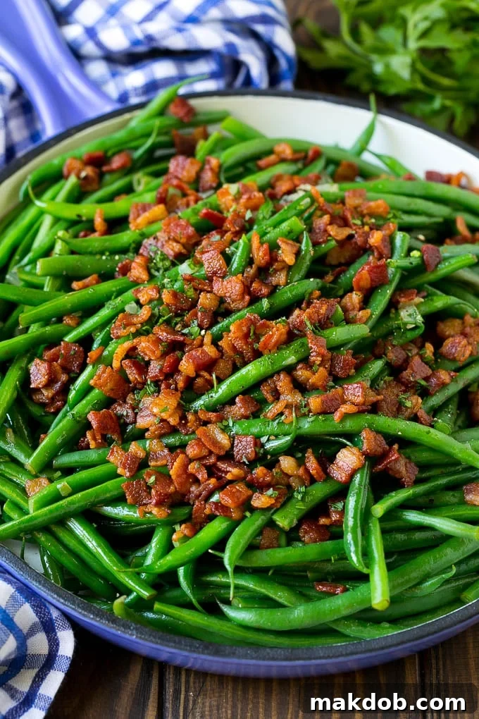 Vibrant green beans with golden crispy bacon and a sprinkle of fresh parsley in a cast-iron skillet, ready to serve.