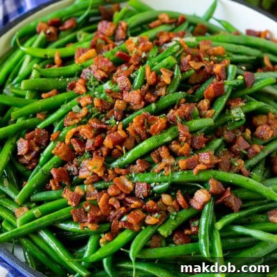 Green beans with bacon in a skillet, topped with parsley.