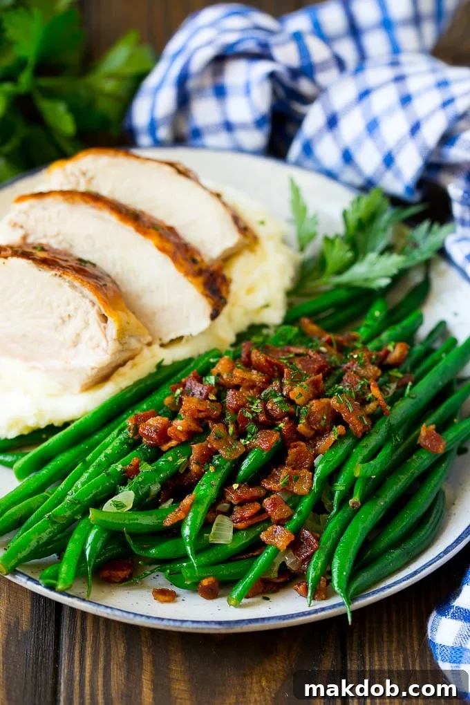 Green beans with bacon served elegantly alongside a classic holiday meal of roasted turkey and creamy mashed potatoes.