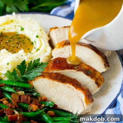 Turkey gravy being poured over sliced turkey breast, showcasing its smooth and rich texture.