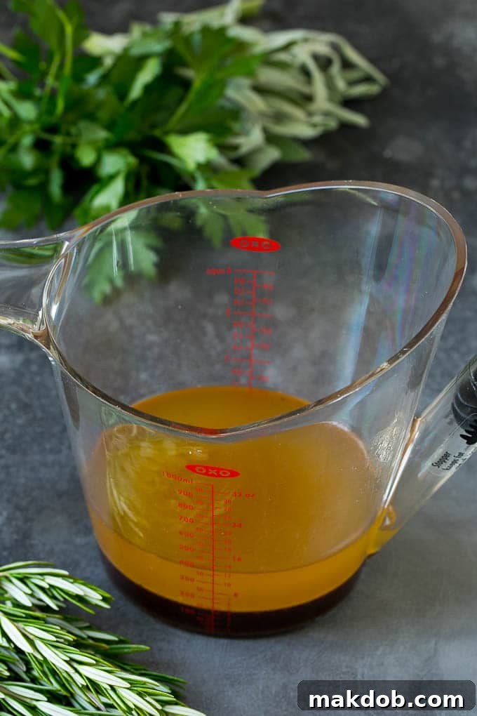 A fat separator filled with turkey drippings, showing the clear flavorful liquid separated from the top layer of fat.