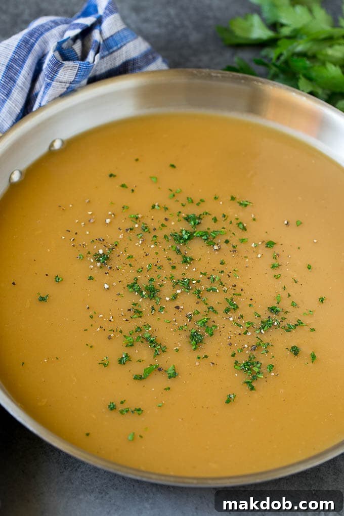 A pan of rich, smooth turkey gravy garnished with fresh parsley and cracked black pepper, ready to serve.