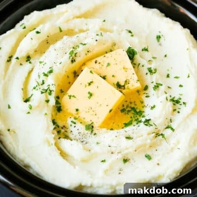 Crock pot mashed potatoes topped with butter and parsley.