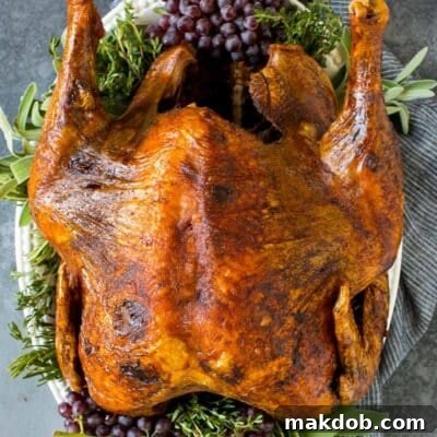 A whole deep fried turkey on a serving platter with herbs.