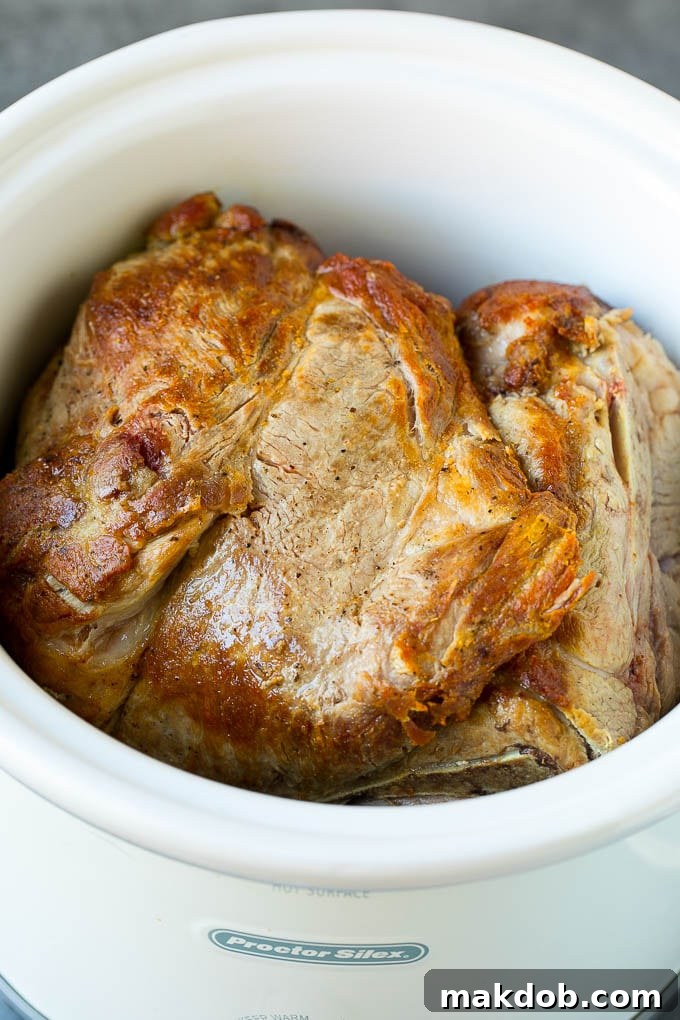 Slow Cooker Pulled Pork Recipe | Crock Pot Pulled Pork #pork #pulledpork #crockpot #slowcooker #dinner #dinneratthezoo A seared pork shoulder roast inside of a slow cooker.