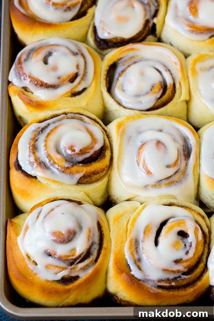 Cinnamon Rolls Recipe | Cinnamon Buns #cinnamon #rolls #pastry #breakfast #brunch #sweets #dinneratthezoo #baking #bread A tray of freshly frosted cinnamon rolls, glistening with cream cheese.