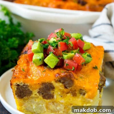 A slice of sausage egg casserole with a garnish of fresh tomatoes.