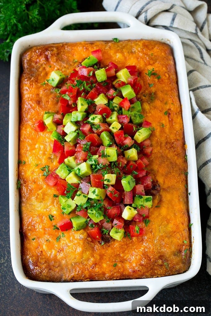 A whole sausage egg casserole, freshly baked and generously topped with vibrant diced avocado and tomatoes, ready for serving.