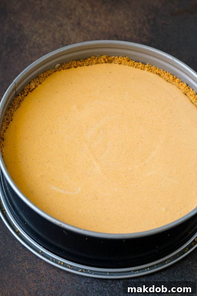 Pumpkin Pie Cheesecake Recipe | Pumpkin Cheesecake #cake #cheesecake #pumpkin #fall #thanksgiving #dessert #dinneratthezoo Creamy pumpkin cheesecake batter poured into a golden brown graham cracker crust in a springform pan, ready for baking.